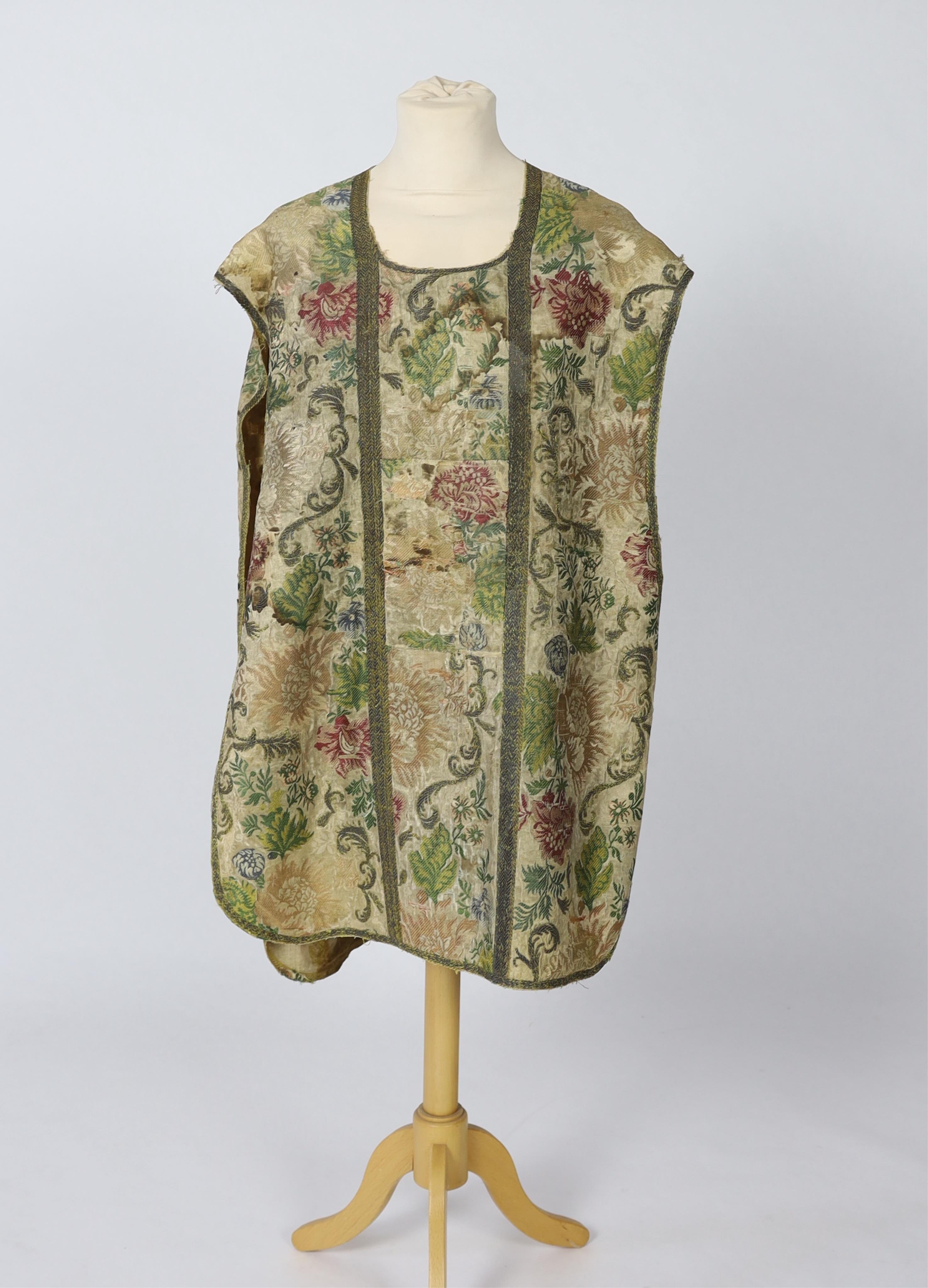 A late 18th century continental, possibly French, silk multi coloured and metallic brocade chasuble, lined with thick linen, edged and panelled with a thick metallic braid, 99cm long